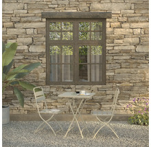 Szene mit Gartentisch, zwei Stühlen, Geschirr und Pflanze vor einer Steinwand