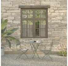 Gartenszene mit Bistrotisch und zwei Stühlen vor einer Steinwand