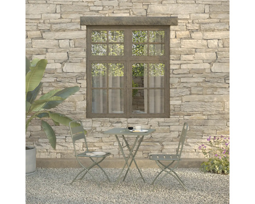 Gartenszene mit Bistrotisch und zwei Stühlen vor einer Steinwand