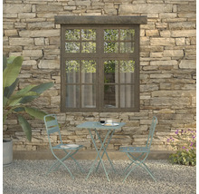 Gartenszene mit Bistrotisch und zwei Stühlen vor einer Steinmauer