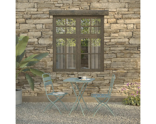 Gartenszene mit Bistrotisch und zwei Stühlen vor einer Steinmauer