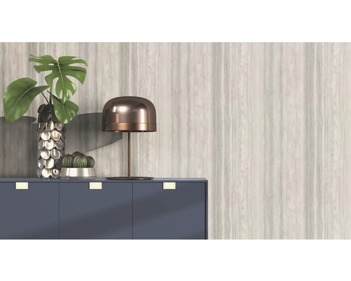 Dekoratives Interieur mit Pflanze, Lampe und Kommode vor einer gemusterten Wand