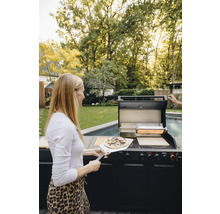 Frau mit Pizza vor einem Gasgrill im Freien