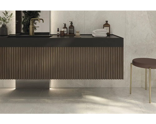 Modernes Badezimmer mit Waschtischunterschrank, Armatur, Pflegeprodukten, Handtüchern und Hocker