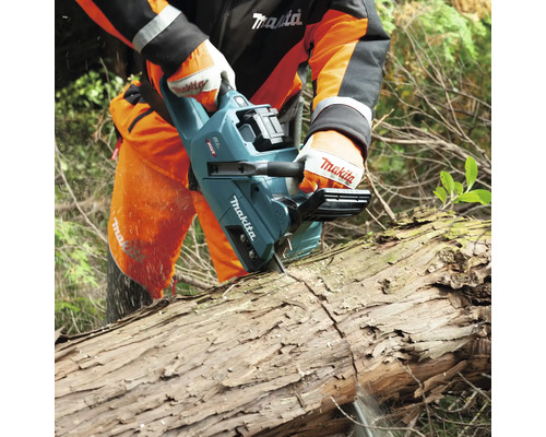 Eine Person sägt mit einer Akku-Kettensäge einen Baumstamm.