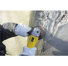 Person schleift eine Betonwand mit einem Winkelschleifer.