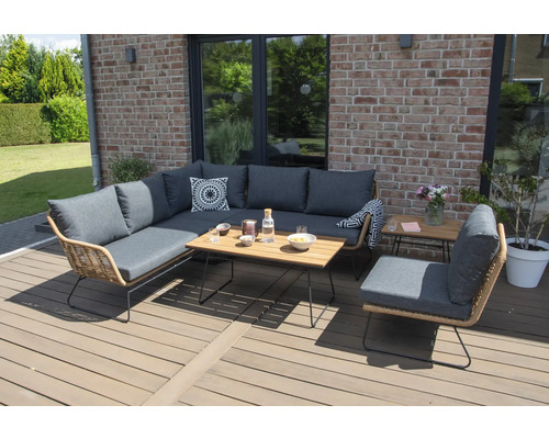 Gartenszene mit einer Loungegruppe aus Rattan mit grauen Polstern und einem Holztisch