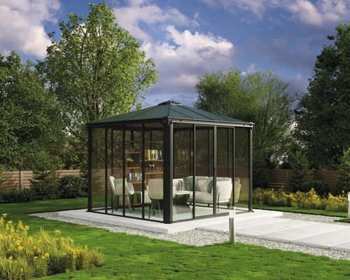 Gartenpavillon mit Glaswänden, Sitzmöbeln und Bücherregal auf einer Terrasse im Garten.