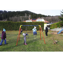 Kinder spielen auf einem Kettler Schaukelgerüst im Garten.