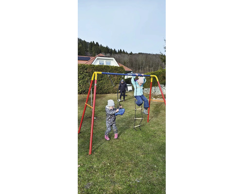 Kinderschaukel mit spielenden Kindern im Garten