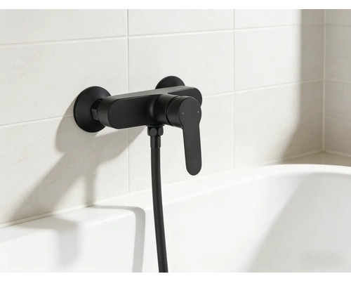 Schwarze Wannenarmatur mit Brauseschlauch an gefliester Wand über Badewanne