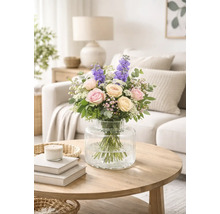 Blumenstrauß mit Rosen und Rittersporn in einer Glasvase auf einem Tisch