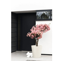 Dekorative Kunstblume mit rosa Blüten in einem Topf vor einem modernen Gebäude.