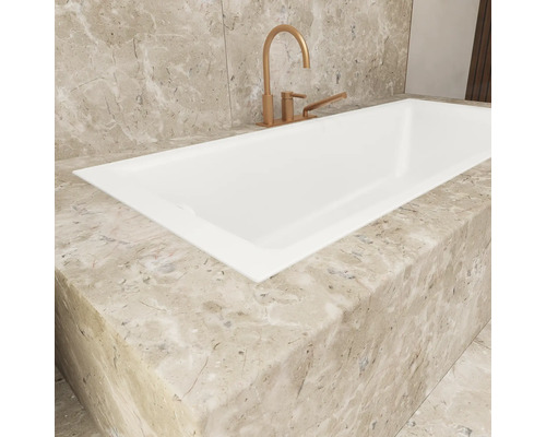 Detailansicht einer Einbaubadewanne mit Armatur und Marmorverkleidung.