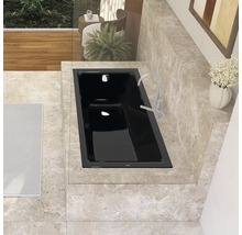 Eingebaute schwarze Badewanne mit Armatur in einem Badezimmer mit Fliesen