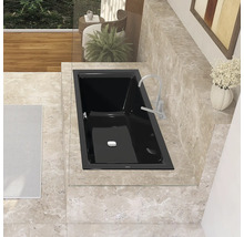 Schwarze Badewanne mit Armatur in einem Badezimmer mit Fliesenboden.