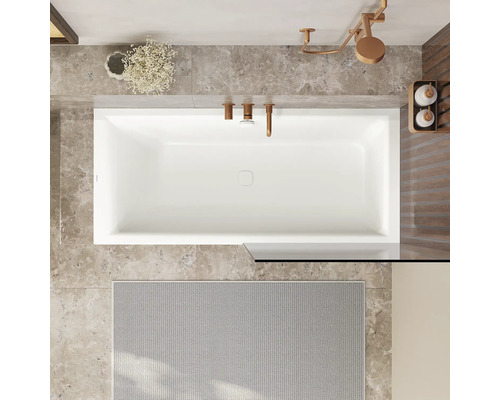 Ansicht von oben auf ein Badezimmer mit Badewanne, Armaturen, Badteppich und Dekoration