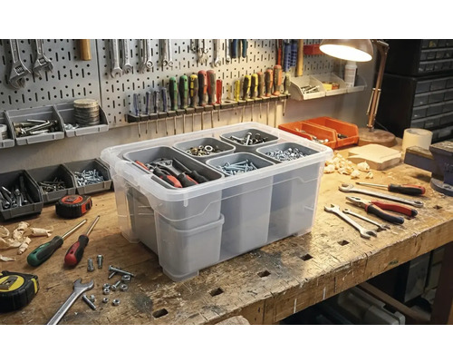 Transparente Aufbewahrungsbox mit Fächern zur Werkzeugorganisation auf einer Werkbank.