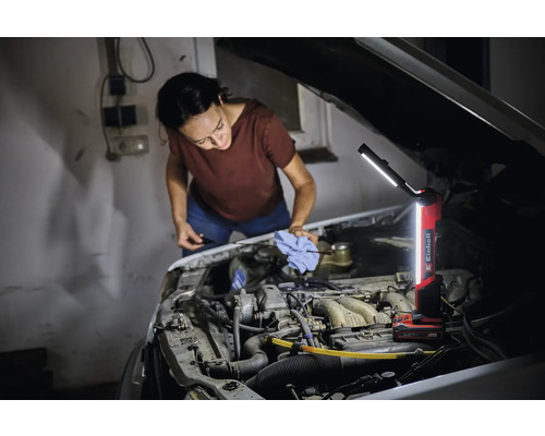 Frau überprüft den Ölstand eines Autos mit einer Einhell Akku-Lampe