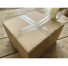 Ein Karton wird mit einem transparenten Klebeband verschlossen.