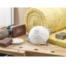 Szene mit Staubschutzmaske, Schleifpapier, Schleifmaschine und Dämmwolle auf einer Werkbank.