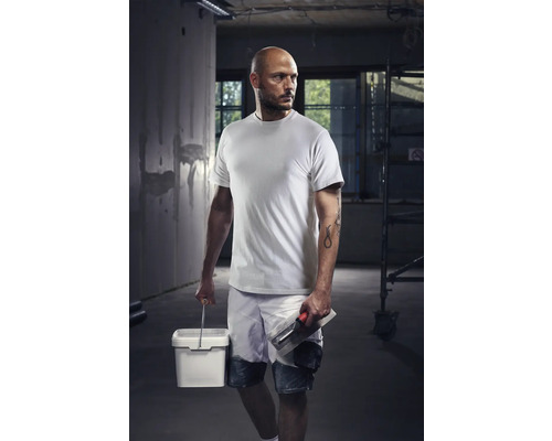 Handwerker mit T-Shirt, Shorts, Eimer und Glättkelle auf einer Baustelle
