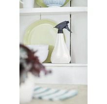 Sprühflasche aus Kunststoff auf einem Regal neben Geschirr