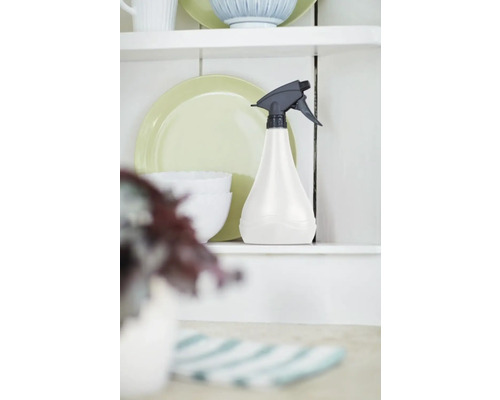 Sprühflasche aus Kunststoff auf einem Regal neben Geschirr