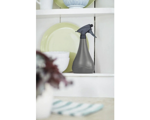 Graue Sprühflasche auf einem Regal mit Geschirr