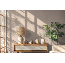 Wohnraum mit Holztisch, Lampe, Vasen und Pflanze vor einer Wand