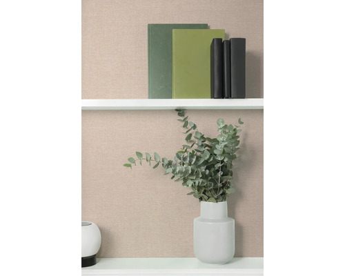 Regal mit Büchern und einer Vase mit Eukalyptus vor einer beigen Tapete