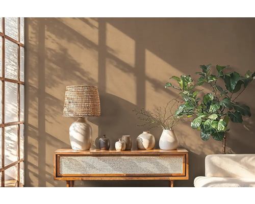 Wohnraum mit Holztisch, Lampe, verschiedenen Vasen und Zimmerpflanze