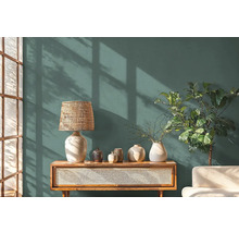 Wohnzimmer mit einer Kommode, einer Lampe, Vasen und einer Zimmerpflanze vor einer Wand