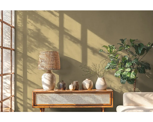 Dekorative Szene mit Tischlampe, Vasen, Tisch und Zimmerpflanze vor einer Wand