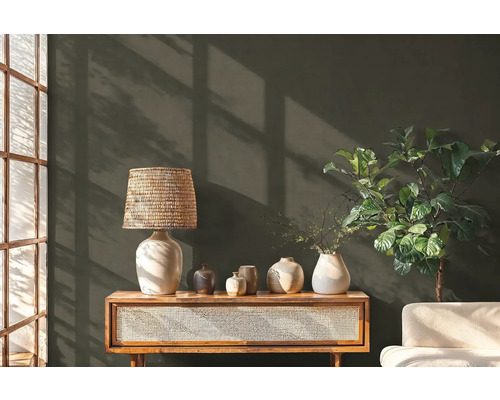 Dekorative Szene mit Lampe, Vasen, Kommode und Zimmerpflanze vor einer Wand
