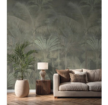 Vliestapete mit Palmenmuster in einem hellen Wohnzimmer hinter einem cremefarbenen Sofa, einer Tischlampe und einer großen Zimmerpflanze.