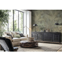 Modernes Wohnzimmer mit heller Couch, Lederhocker und Vliestapete mit Palmenmotiv an der Wand hinter einem Sideboard.