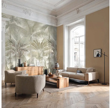 Helles Wohnzimmer mit großflächiger Fototapete mit Palmenmotiv, Sofa, Sesseln, Holzmöbeln und Fischgrätparkett.