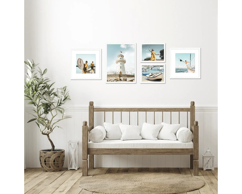 Wohnraum mit Holzbank, Pflanze im Korb und Bilder mit Küstenmotiven an der Wand