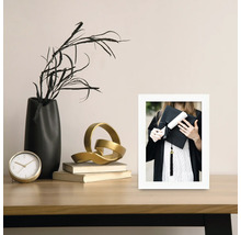 Dekorative Szene mit Uhr, Vase, Skulptur, Büchern und einem gerahmten Abschlussfoto