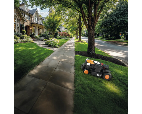 Ein Rasenmähroboter mäht den Rasen vor einem Wohnhaus.