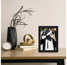 Dekoratives Foto mit schwarzem Rahmen auf einem Tisch, das eine Absolventin mit Hut und Urkunde zeigt