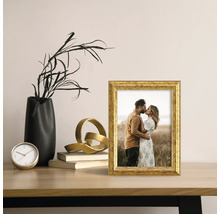 Dekorativer goldfarbener Bilderrahmen mit Foto auf einem Tisch arrangiert