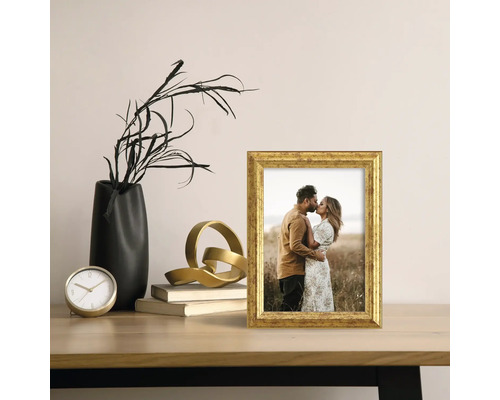 Dekorative Szene mit einem goldenen Bilderrahmen, einer schwarzen Vase und einer goldenen Skulptur