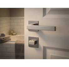 Tür mit modernem Türdrücker und Badezimmer im Hintergrund