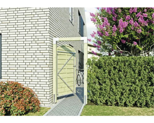 Holztor neben einem Haus mit Ziegelmauer und blühendem Baum