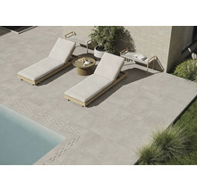 Terrasse mit Steinplatten, zwei Liegestühlen und einem kleinen Tisch neben dem Pool