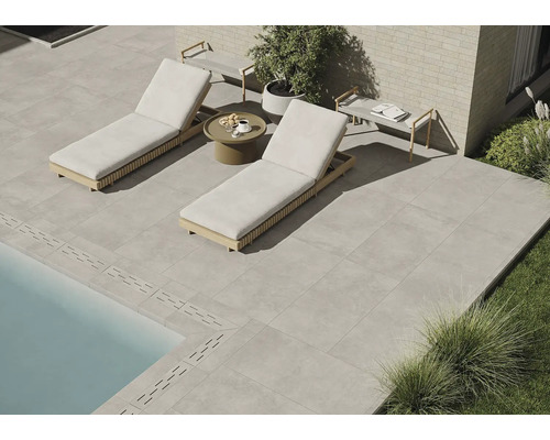 Terrasse mit Steinplatten, zwei Liegestühlen und einem kleinen Tisch neben dem Pool