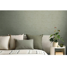 Modernes Schlafzimmer mit Kissen in Grün und Creme vor einer strukturierten olivgrünen Wand und einer Anthurium Pflanze.