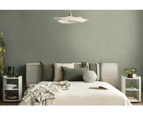 Modernes Schlafzimmer mit strukturierter salbeigrüner Tapete, weißem Bett mit Dekokissen, blütenförmiger Pendelleuchte und Nachttischen.